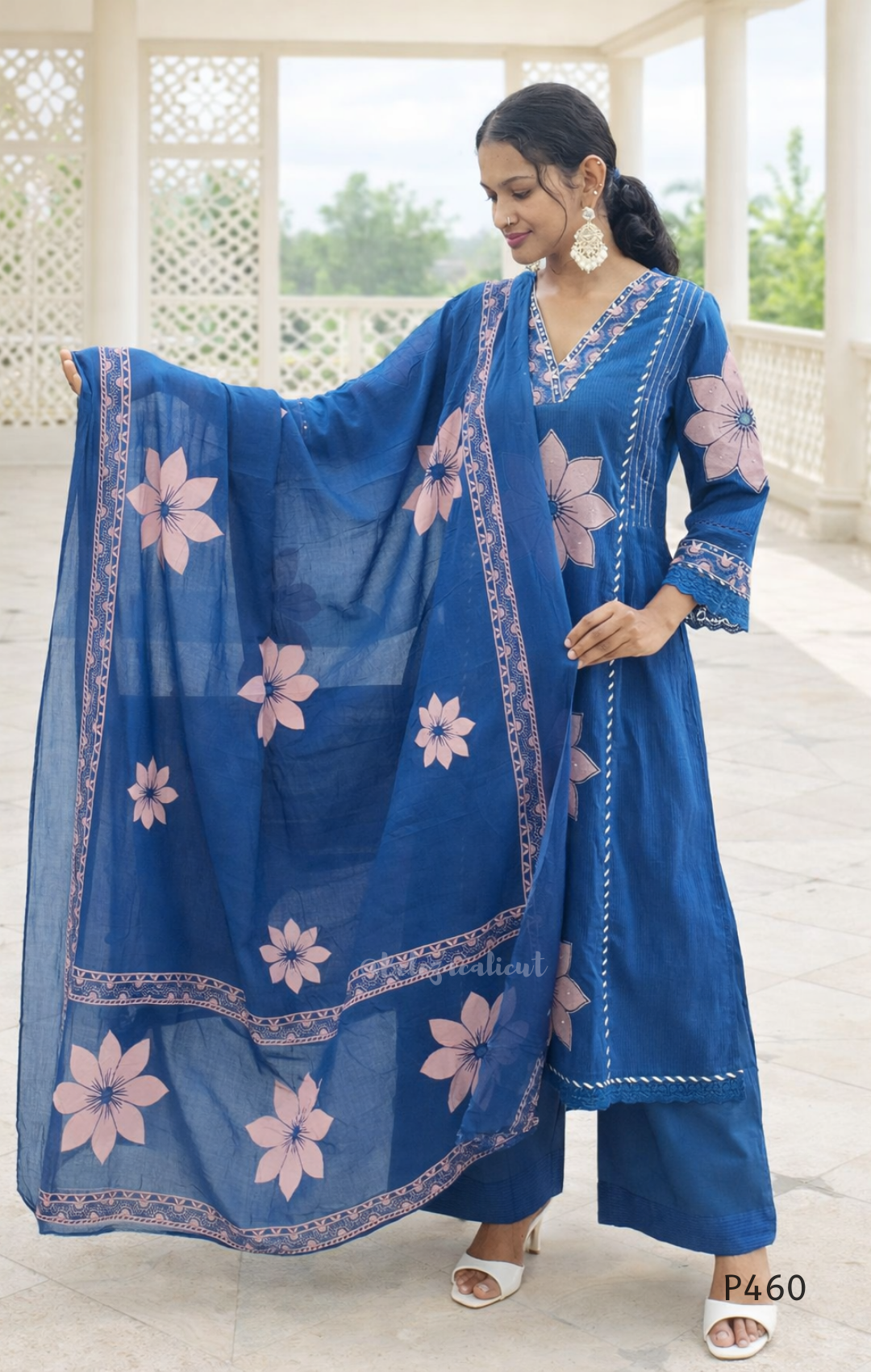 Woman wearing a blue traditional outfit with pink floral patterns outdoors.