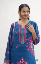 Woman wearing a blue embroidered traditional outfit with pink and white patterns on a plain background
