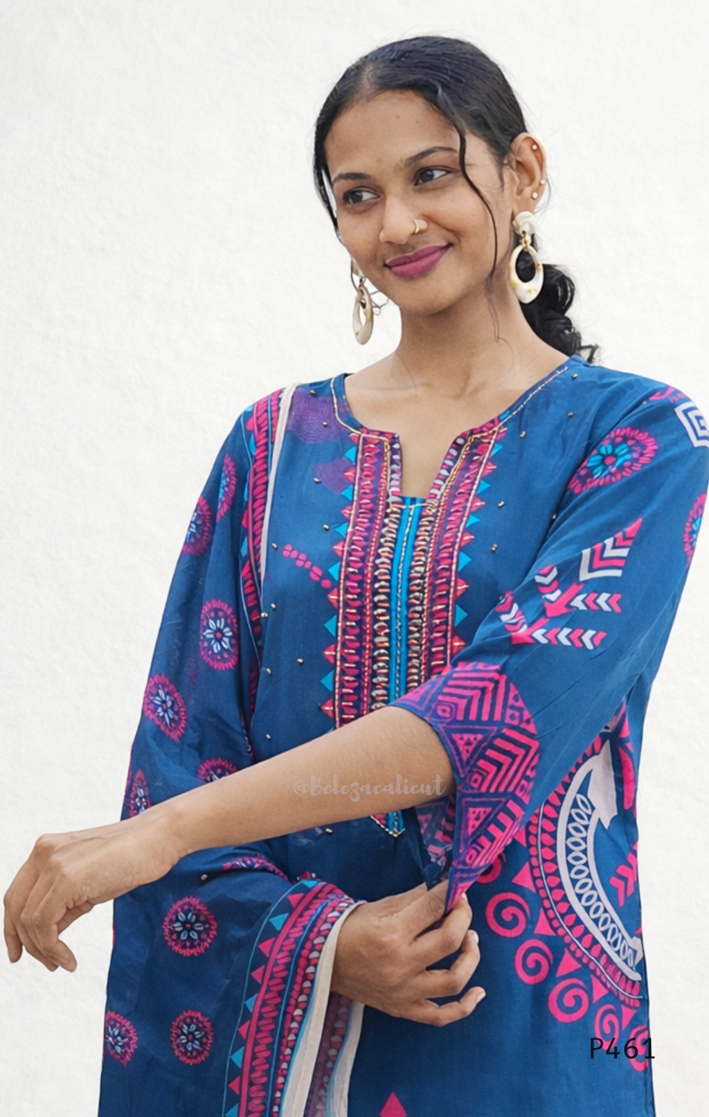 Woman wearing a blue patterned dress with a white background
