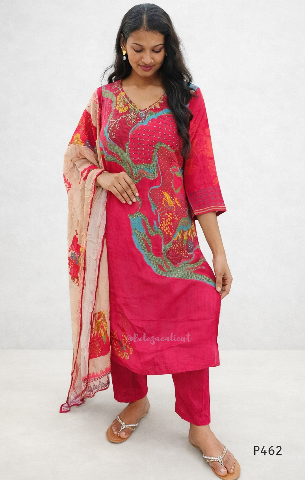 Woman wearing a pink embroidered traditional outfit with a beige dupatta on a white background