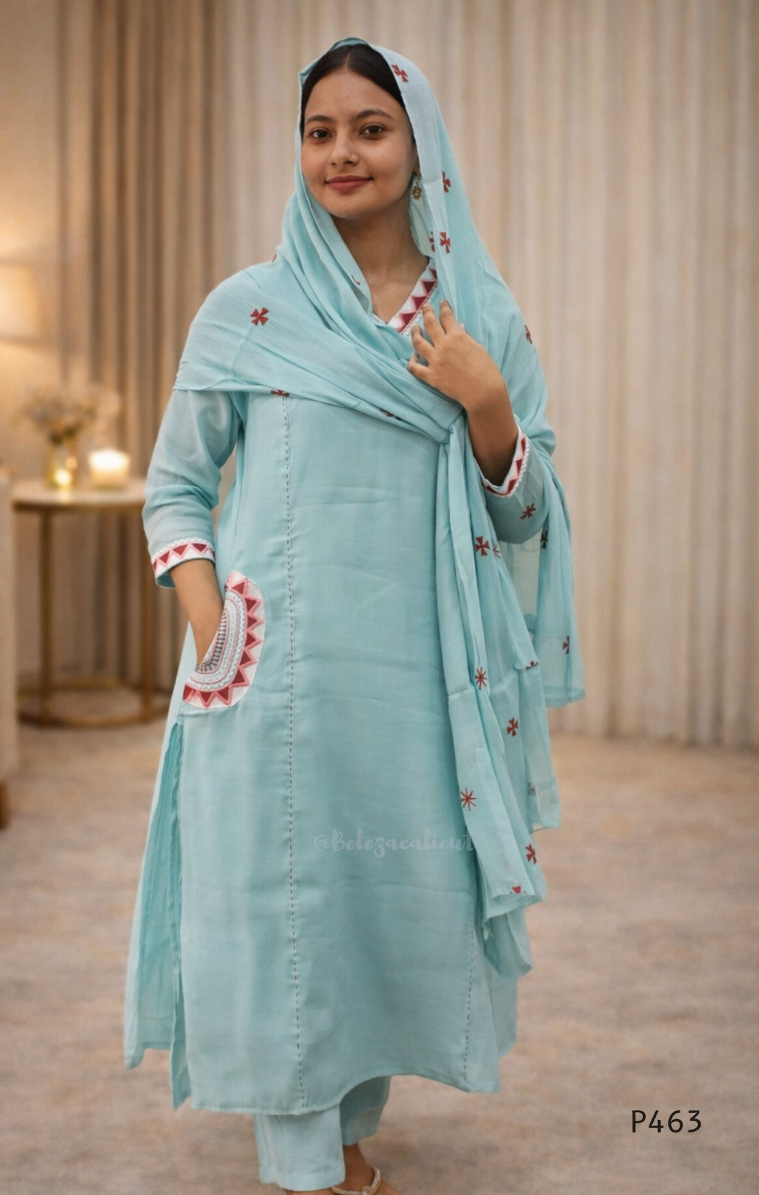 Woman wearing a light blue traditional outfit with a matching dupatta indoors.