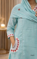 Light blue traditional outfit with red and white embroidery, blurred background
