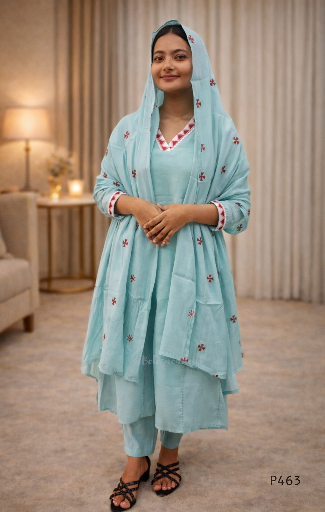 Woman wearing a light blue traditional outfit with a matching dupatta in a room.