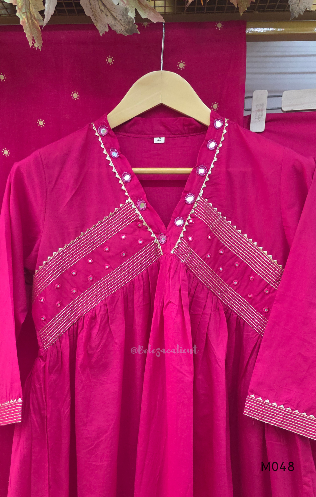 Rani pink cotton churidar suit set with matching bottom and dupatta, mirror detail V-neckline, gold line work on yoke, and festive casual styling.