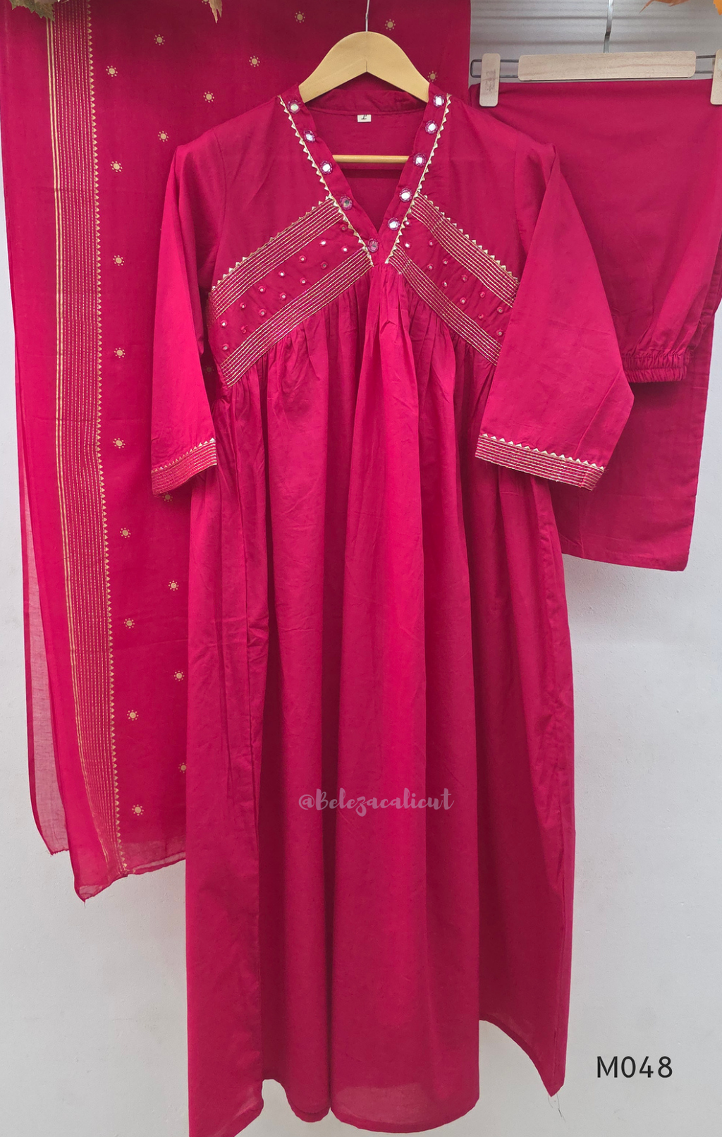 Rani pink cotton churidar suit set with matching bottom and dupatta, mirror detail V-neckline, gold line work on yoke, and festive casual styling.