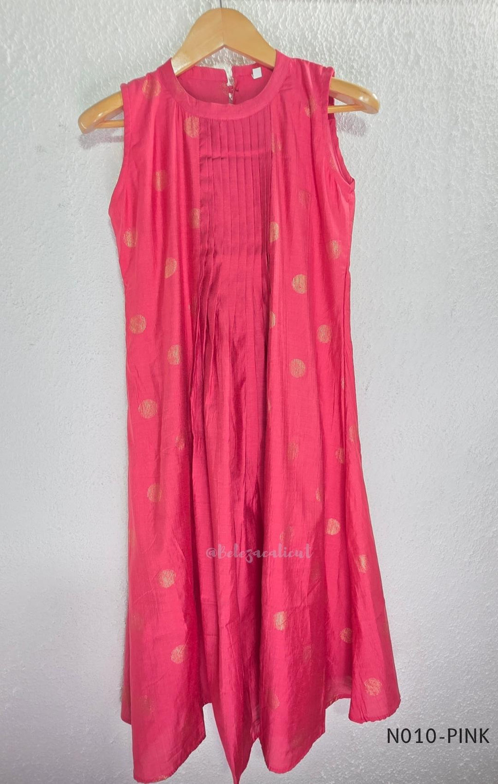Raspberry pink Vertigan silk coord set with sleeveless pleated A-line top, gold circular side motifs and matching straight pants.