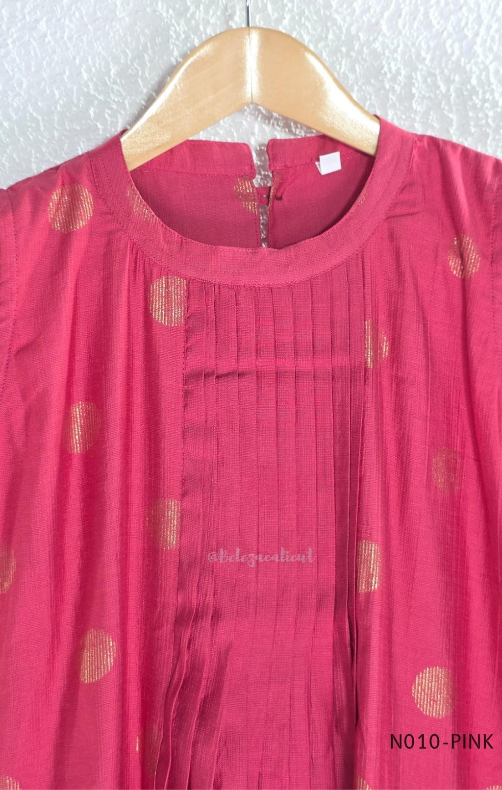 Raspberry pink Vertigan silk coord set with sleeveless pleated A-line top, gold circular side motifs and matching straight pants.