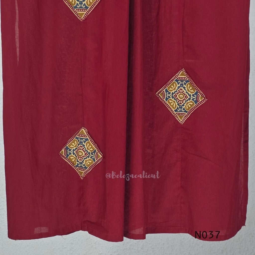 Raspberry red cotton 3-piece churidar set with a printed V-neck border, mirror-and-tassel yoke, diamond motifs, printed sleeves, straight pants and a printed dupatta.
