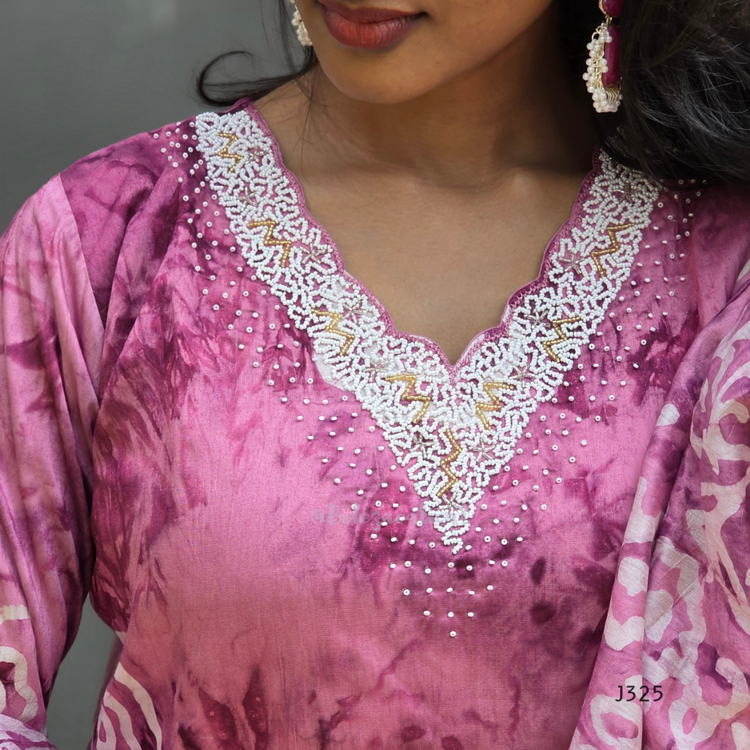 Close-up of a pink traditional outfit with white embroidery on a gray background
