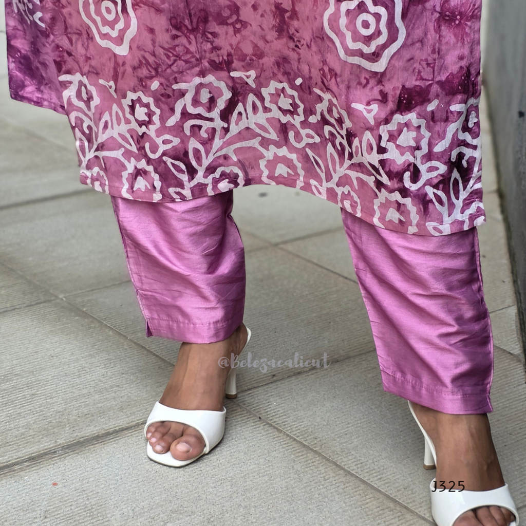 Person wearing a pink floral top and pants with white sandals on a tiled floor.