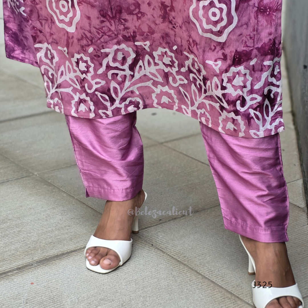 Person wearing a pink floral top and pants with white sandals on a tiled floor.