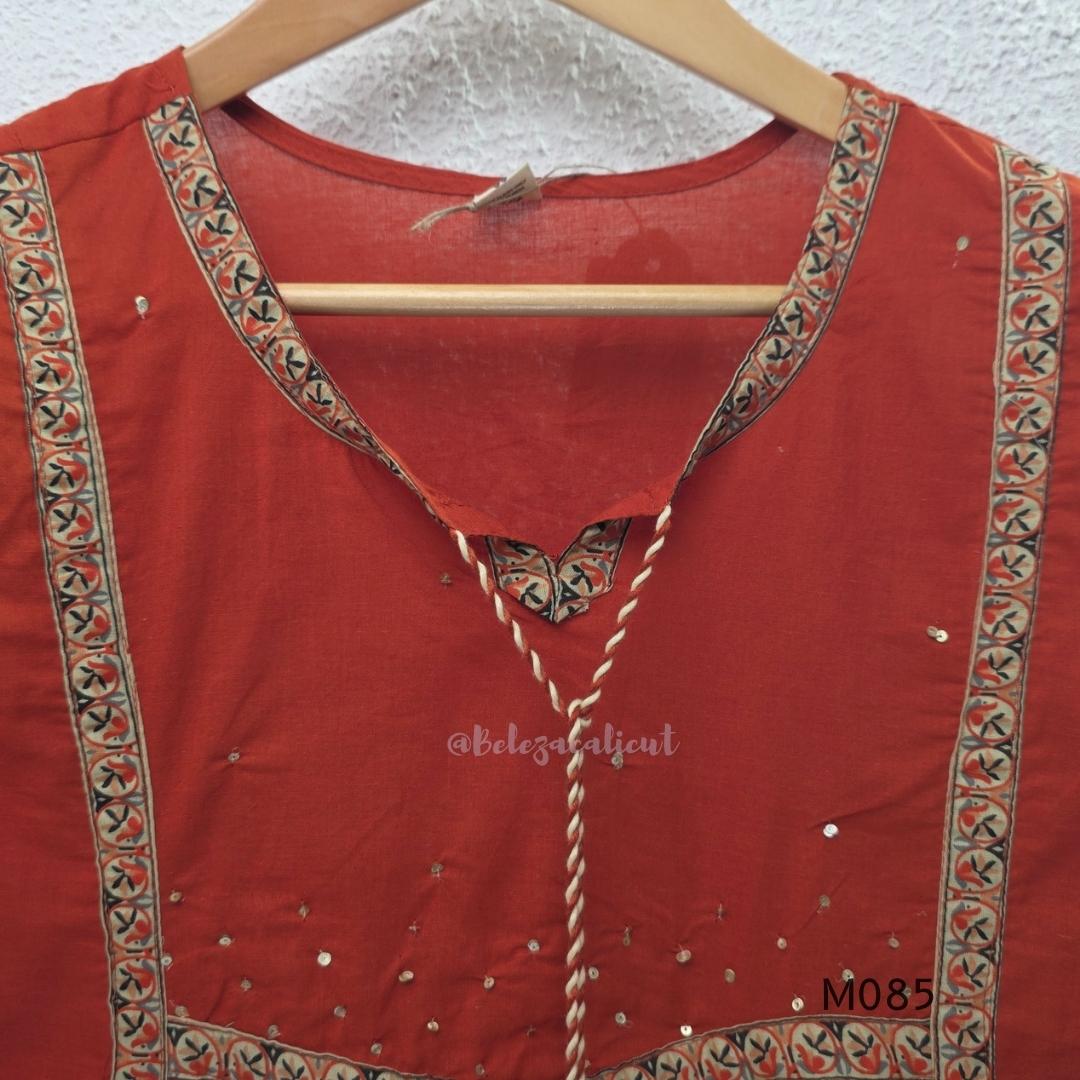 Rust-orange cotton churidar set with decorative patchwork-style trims, gathered yoke, straight pants and printed dupatta.