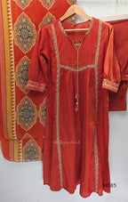 Rust-orange cotton churidar set with decorative patchwork-style trims, gathered yoke, straight pants and printed dupatta.