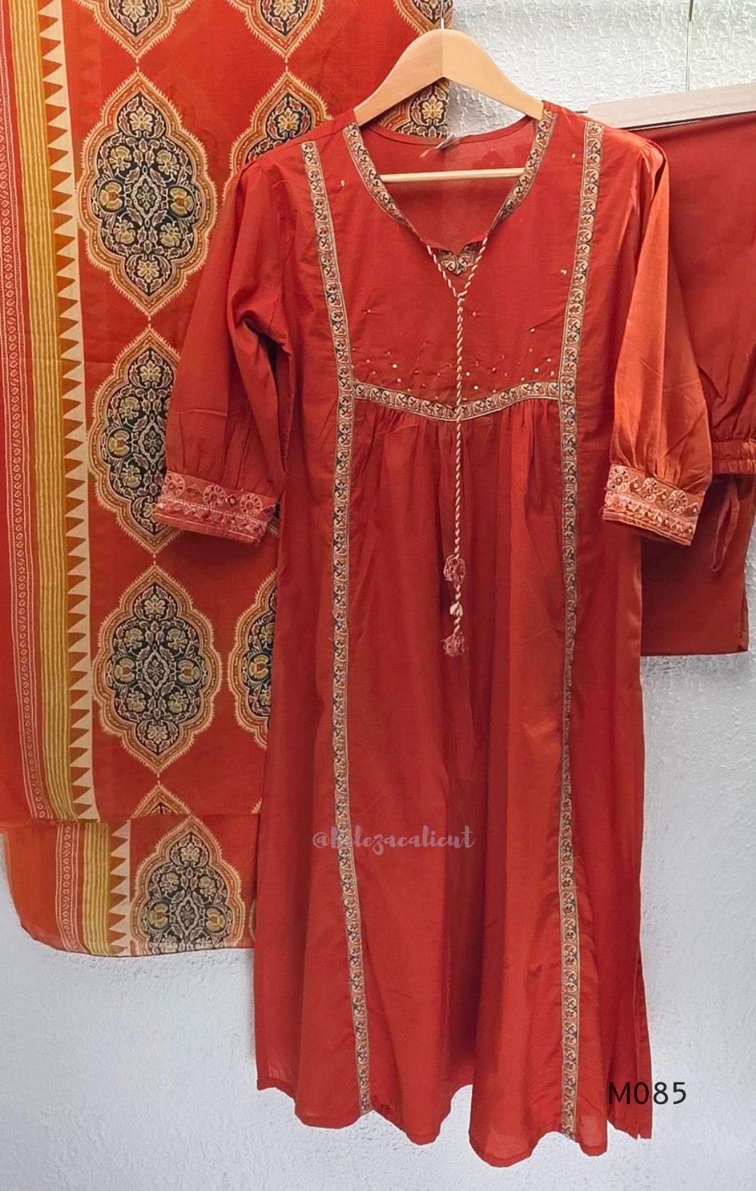 Rust-orange cotton churidar set with decorative patchwork-style trims, gathered yoke, straight pants and printed dupatta.