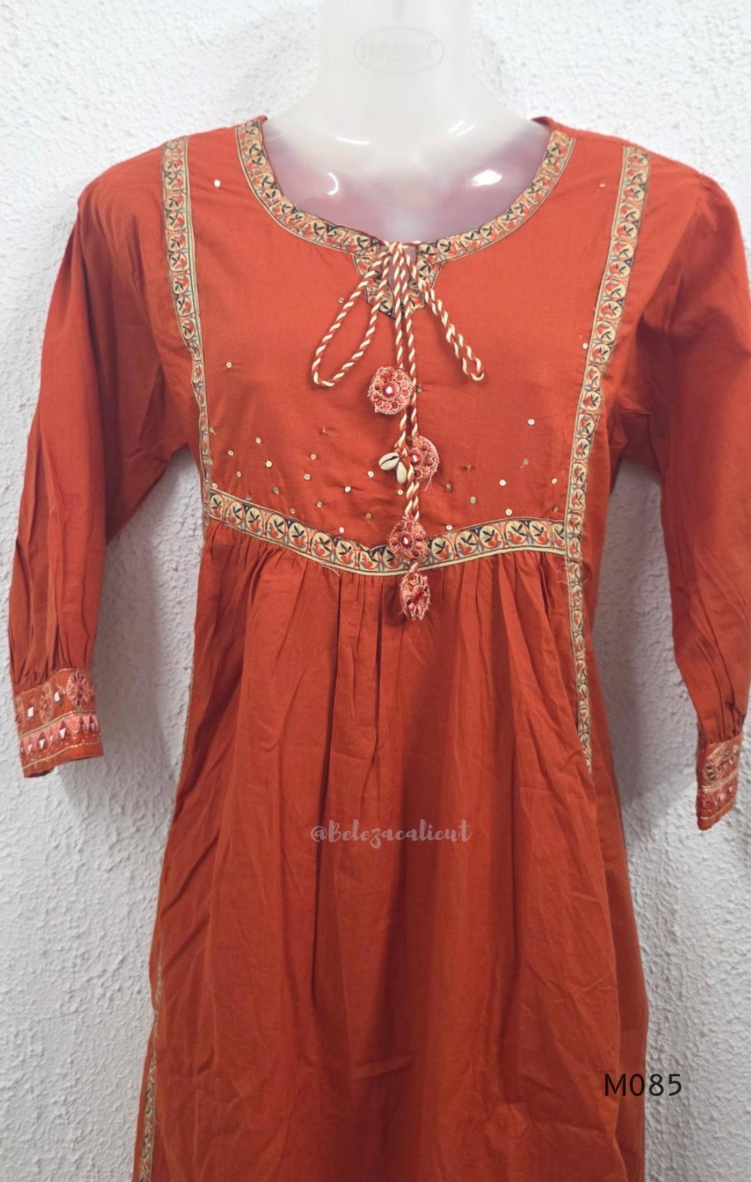Rust-orange cotton churidar set with decorative patchwork-style trims, gathered yoke, straight pants and printed dupatta.