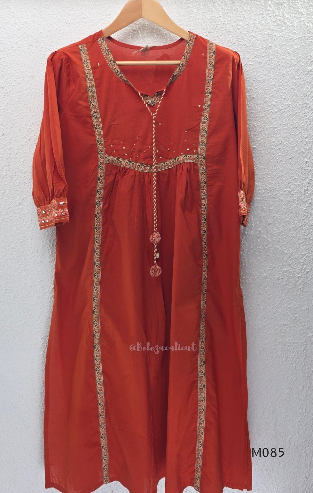 Rust-orange cotton churidar set with decorative patchwork-style trims, gathered yoke, straight pants and printed dupatta.