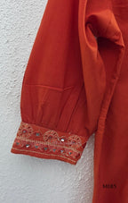 Rust-orange cotton churidar set with decorative patchwork-style trims, gathered yoke, straight pants and printed dupatta.