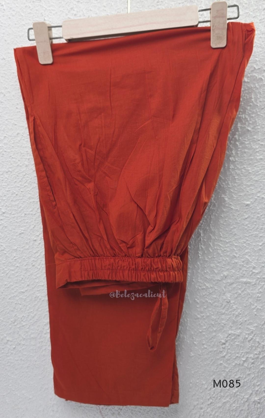Rust-orange cotton churidar set with decorative patchwork-style trims, gathered yoke, straight pants and printed dupatta.