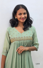 Woman wearing a light green dress with intricate detailing on a white background