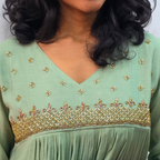 Green dress with gold embroidery on a plain background