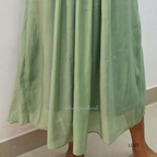Green fabric draped over a person on a plain background