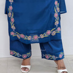 Blue embroidered outfit with white sandals on a light background
