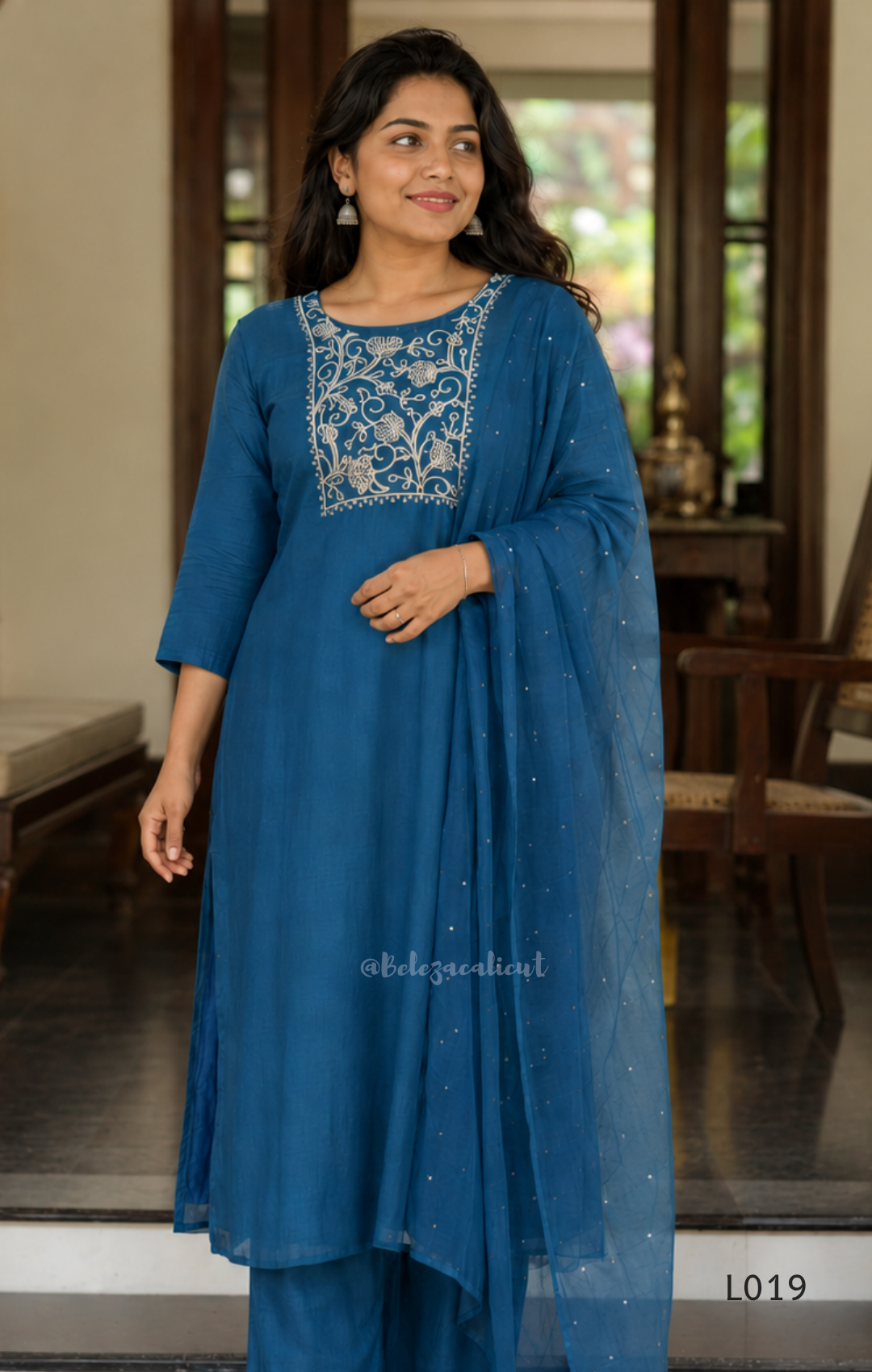 Deep teal blue silk blend 3-piece churidar set with square white floral threadwork embroidery yoke with bead droplet border, straight cut kurti with 3/4 sleeves, matching plain teal bottom with drawstring, and teal chiffon dupatta with scattered silver sequin dots, Indian ethnic wear from Beleza Calicut