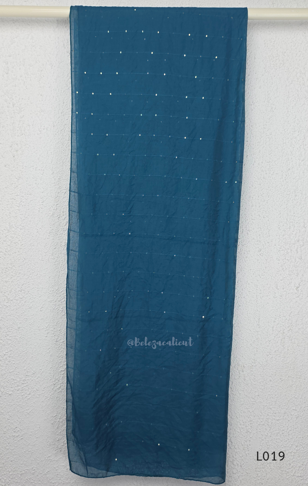 Deep teal blue silk blend 3-piece churidar set with square white floral threadwork embroidery yoke with bead droplet border, straight cut kurti with 3/4 sleeves, matching plain teal bottom with drawstring, and teal chiffon dupatta with scattered silver sequin dots, Indian ethnic wear from Beleza Calicut