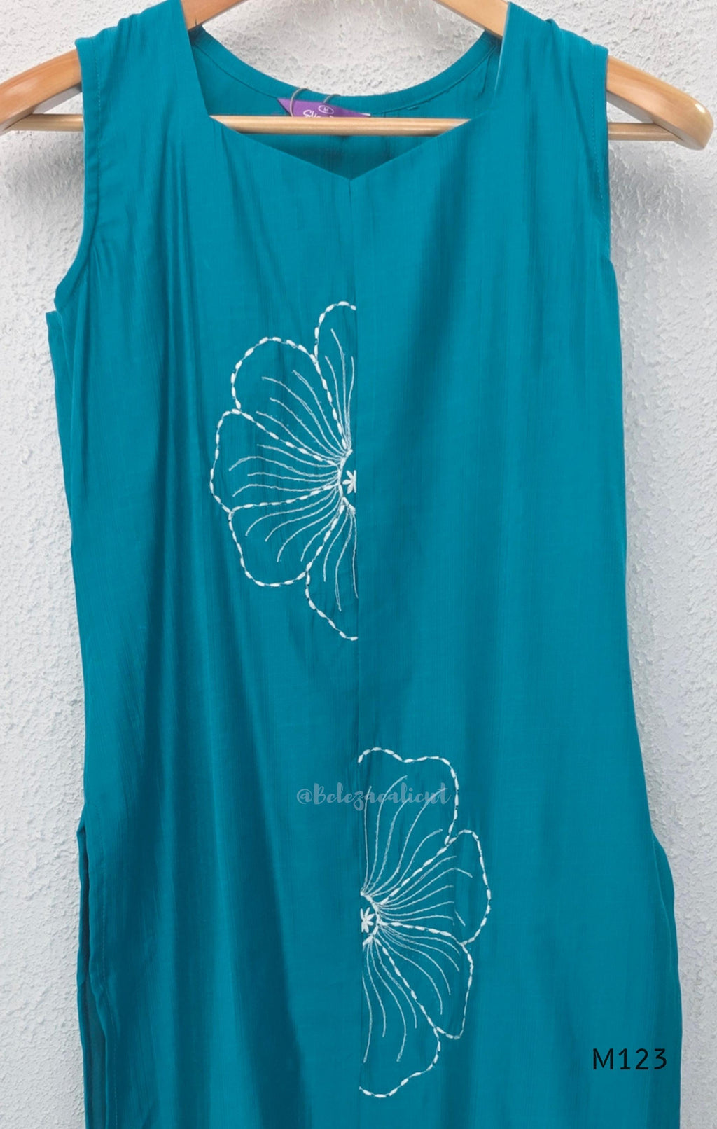eal blue Vertigan silk coord set with white floral embroidery and straight pants.