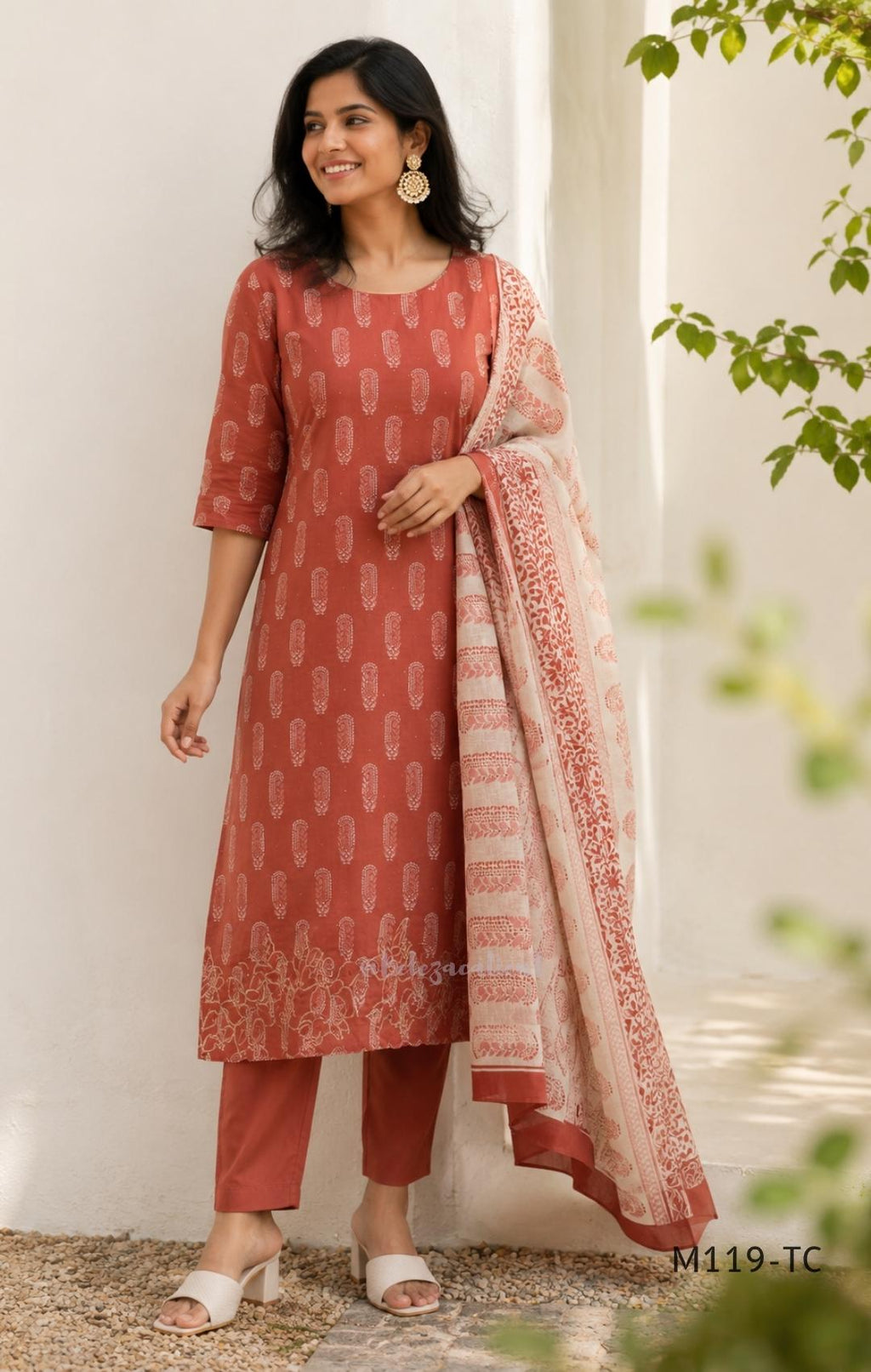 Terracotta Cotton Silk churidar set with paisley motifs, floral embroidered hem, matching straight pants and cream printed dupatta.