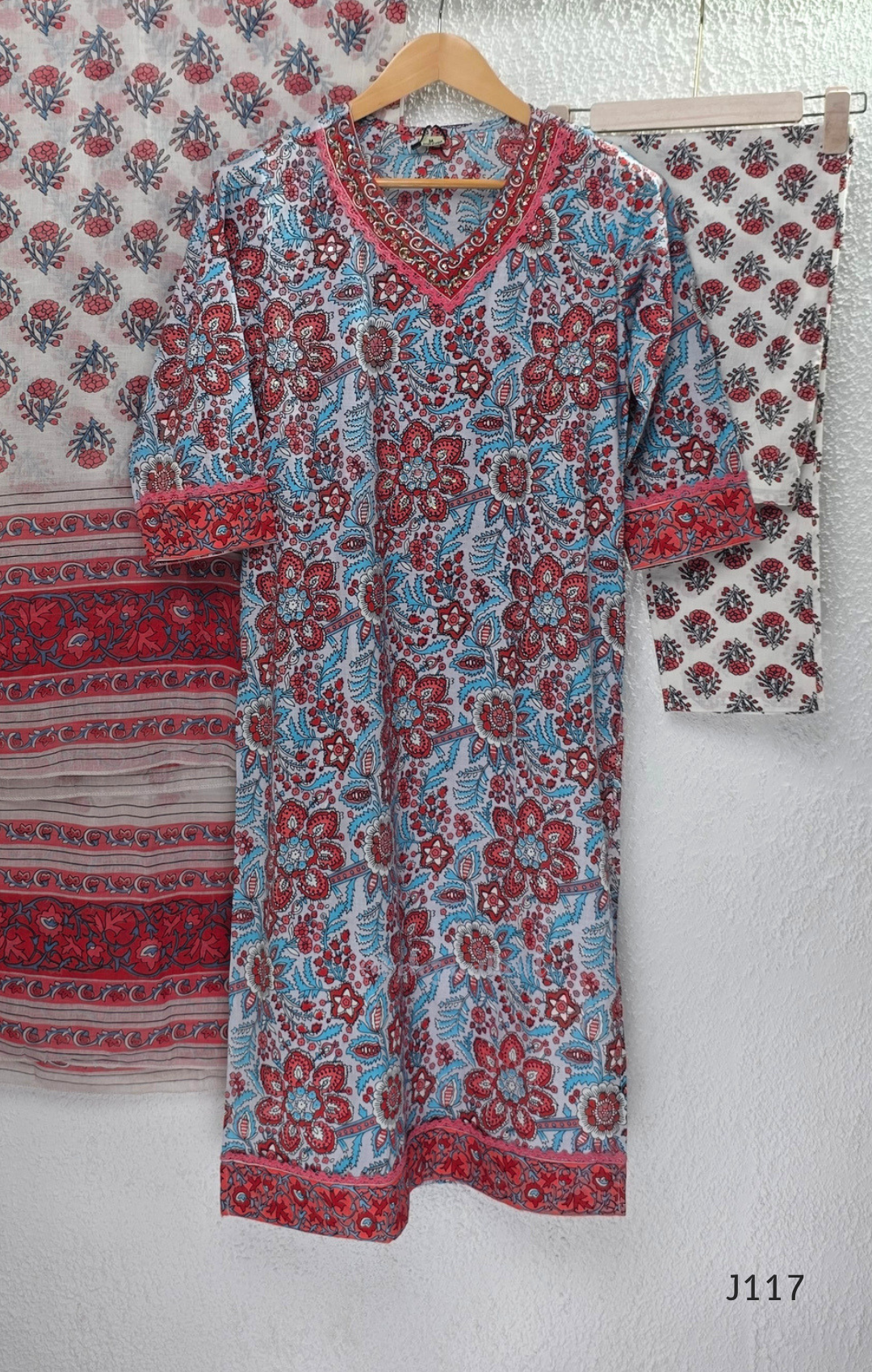 White ivory cotton 3-piece churidar set with dense red and blue kalamkari-style block print, gold sequin V-neckline, lace cuff, and printed dupatta with bold red border.