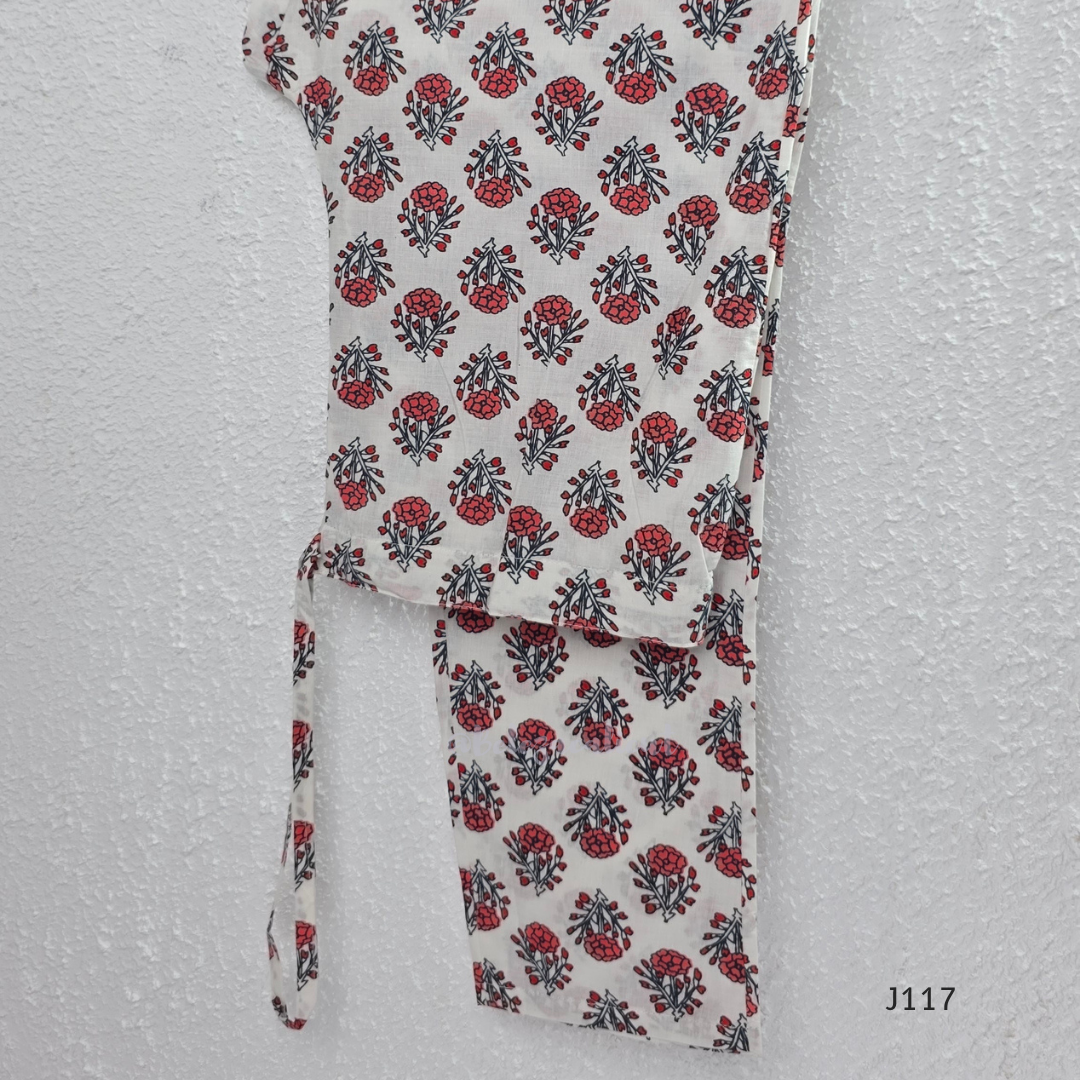 White ivory cotton 3-piece churidar set with dense red and blue kalamkari-style block print, gold sequin V-neckline, lace cuff, and printed dupatta with bold red border.