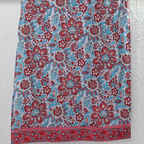 White ivory cotton 3-piece churidar set with dense red and blue kalamkari-style block print, gold sequin V-neckline, lace cuff, and printed dupatta with bold red border.