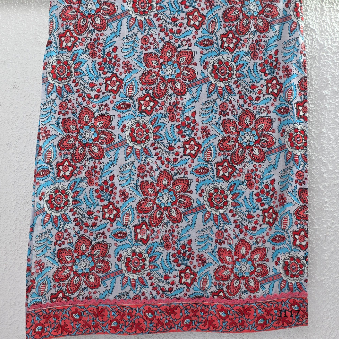 White ivory cotton 3-piece churidar set with dense red and blue kalamkari-style block print, gold sequin V-neckline, lace cuff, and printed dupatta with bold red border.