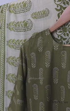 Olive green Cotton Silk churidar set with printed motifs, embroidered floral hem and cream-and-olive printed dupatta.
