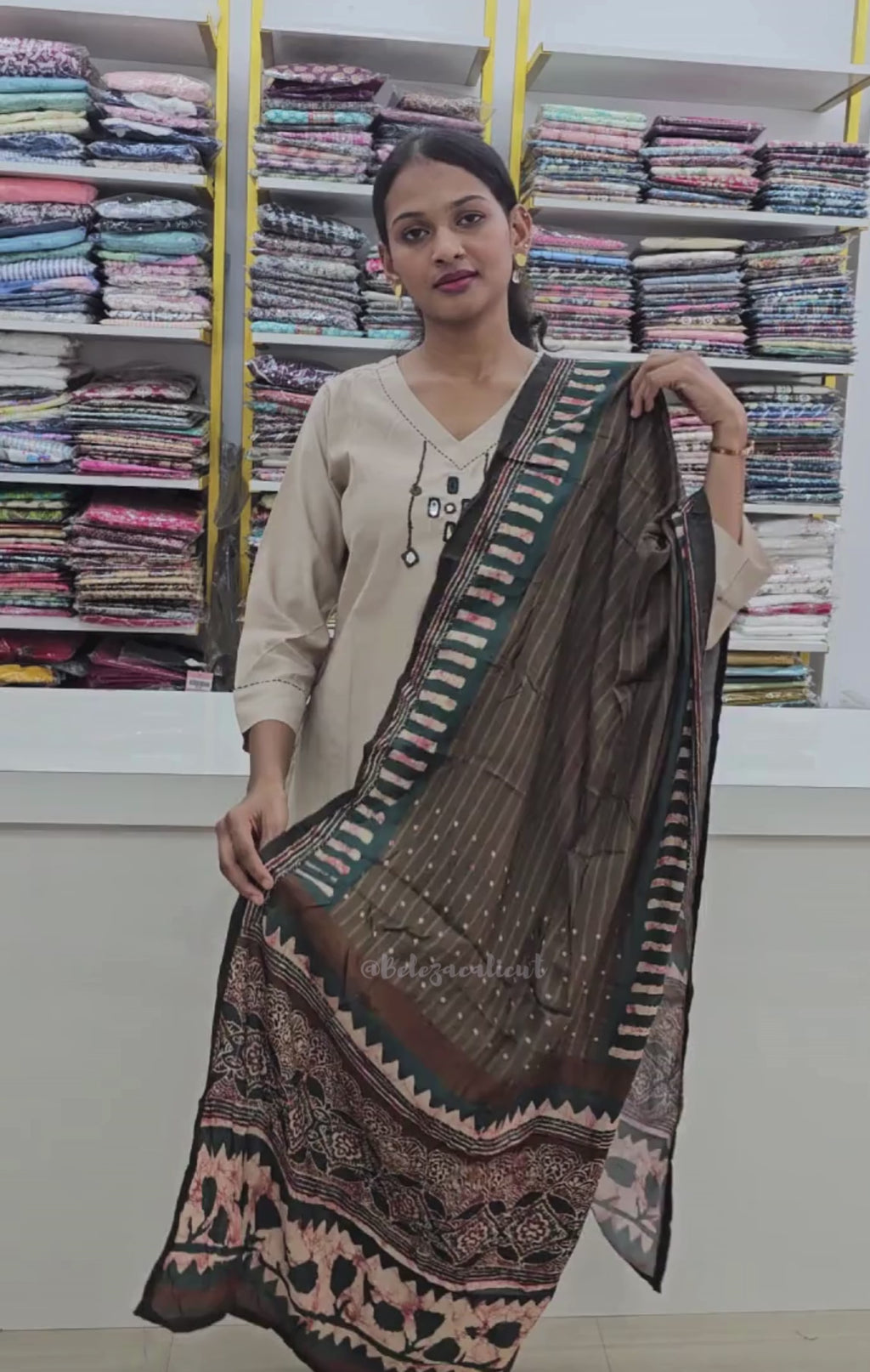 Woman wearing a beige kurta with a brown and black patterned dupatta on a clothing store background
